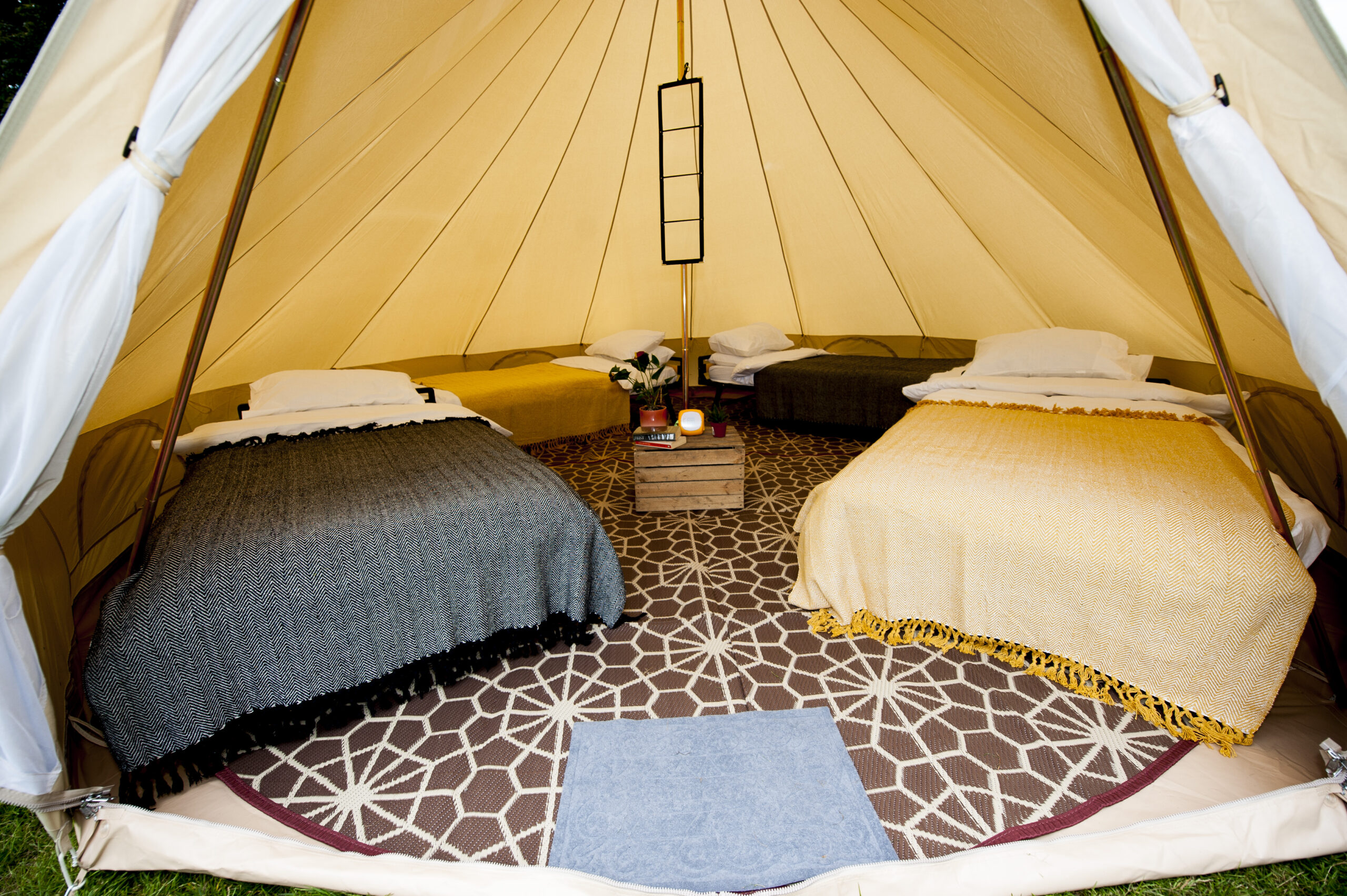 The inside of a bell tent with 4 beds, bedding and accoutrements
