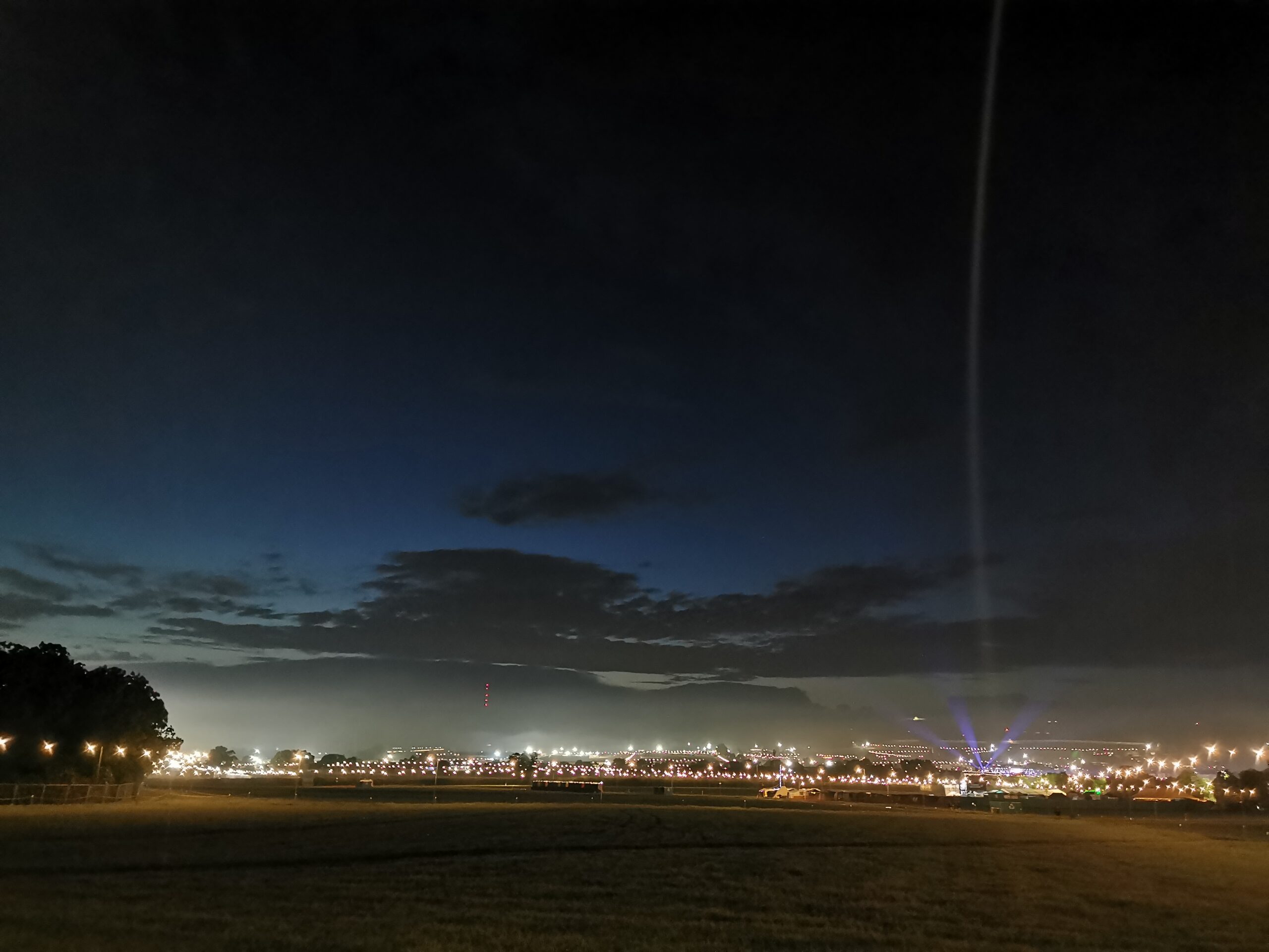 Bell tent glamping village across a field at night.